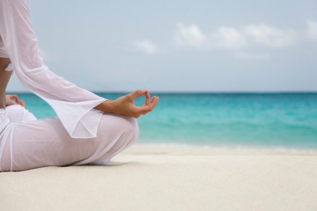 woman meditating on the beach